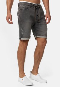 Graue Denim-Shorts mit einem leicht abgenutzten Finish, fünf Taschen, umgeschlagenen Säumen und einem Kordelzug an der Taille.
