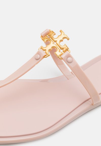 Pink flat sandals made of smooth plastic with a gold decorative accent in the shape of a cross, featuring a minimal design.