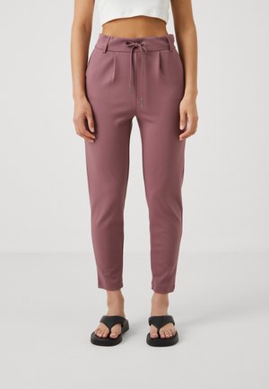 Töjbara, smalnande mjukisbyxor i mauve med dragsko i midjan, sidfickor och en slät yta. Bärs med svarta flip-flop-sandaler.