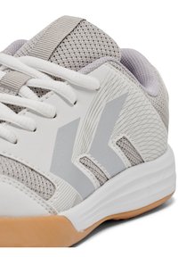 Baskets de sport gris clair avec une tige en maille texturée, des accents synthétiques blancs et une semelle en caoutchouc naturel. Lignes de design distinctives présentes.