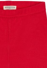 Rode katoenlegging met een gladde textuur, voorzien van een elastische tailleband en een label dat aan de bovenkant in het midden is gestikt.