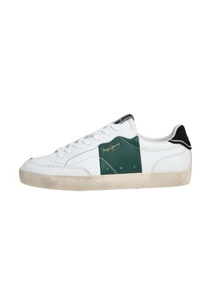 White sneaker with green suede detail, black accents on the heel, white laces, and textured rubber sole. Gold logo on the side.