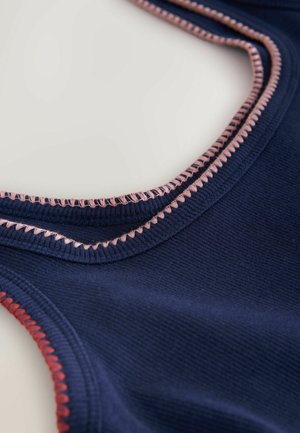 Tuvaļskats uz tumši zilas ribotas auduma ar rozā un sarkanu pāršuvumu izšuvumiem, kas izceļ apkakles un roku ieloku malas.