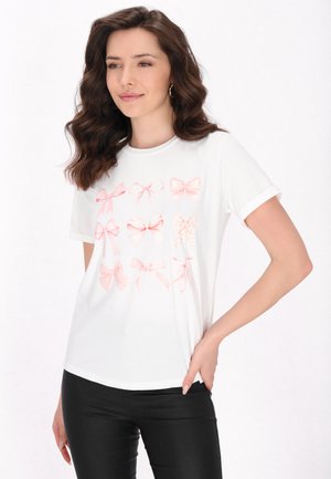 Hvid t-shirt med et mønster af forskellige lyserøde sløjfer, korte ærmer, rund halsudskæring og blød bomuldsstruktur.