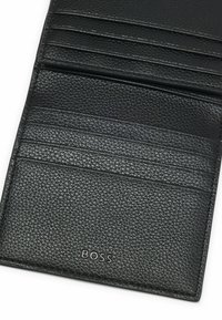 Black leather wallet with a textured finish, featuring multiple card slots and a debossed brand logo. Compact rectangular design.