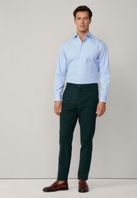 Light blue striped shirt with a button-down collar, paired with dark green slim-fit trousers and brown leather shoes. Simple design, tailored fit.