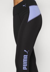 Svarta atletiska leggings med en ljuslavendelfärgad panel och sömmar, med en framträdande vit Puma-logotyp på benet. Stretchig tyg.