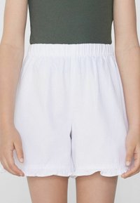 Witte katoenen shorts met een elastische tailleband, met een gerimpelde zoom, voorgesteld tegen een neutrale achtergrond.