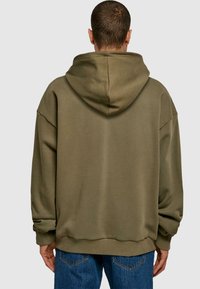 Olivgrön överdimensionerad hoodie med mjuk textur, huva och ribbade ärmslut. Har en rak nederkant och avslappnad silhuett, designad för komfort.