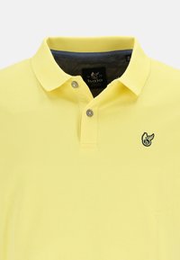 Polo giallo in misto cotone con colletto pieghevole, due bottoni e interno collo blu. Presenta un piccolo logo sul petto.