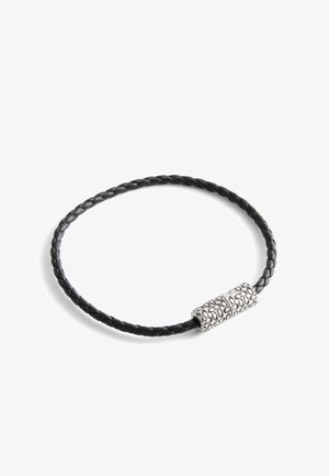 Pulsera de cuero trenzado negro con un cierre cilíndrico de plata grabado con un patrón floral, presentada sobre un fondo blanco.