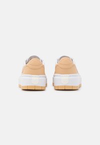 Sneakers med en ovandel i beige läder med vita detaljer, tjock vit mellansula och gummisula med ett rutmönster.