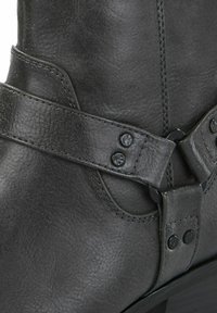 Juodas odinis kulkšninis botas su lygiu paviršiumi, apsuktos juostos dizainu ir dekoratyviniais metaliniais akcentais. Dydžio ir stiliaus detalės nematomos.