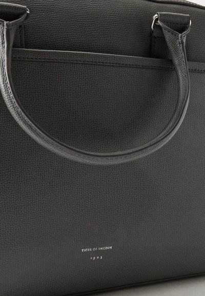 Sac fourre-tout en cuir texturé noir avec poignées arrondies et logo "Tiger of Sweden 1903" embossé sur le devant.