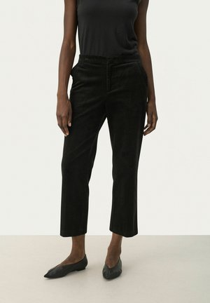 Black corduroy pants with a straight leg cut, featuring an elastic waistband and side pockets, paired with black flat shoes.