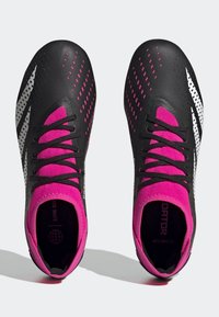 Mustat ja vaaleanpunaiset urheilu kengät, joissa on teksturoitu päällinen, valkoiset yksityiskohdat ja pistekuviot, nauhakiinnitys ja pehmustettu sisustus.