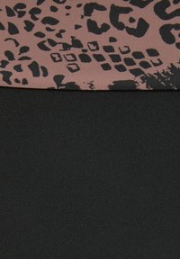 Melnā auduma apakša, ar rakstainu brūnu un melnu augšdaļu, kas satur abstraktas leoparda formas un tekstūras.