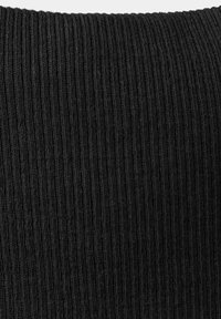 Gros plan d'un tissu tricoté noir à côtes montrant un motif texturé vertical et des coutures serrées.