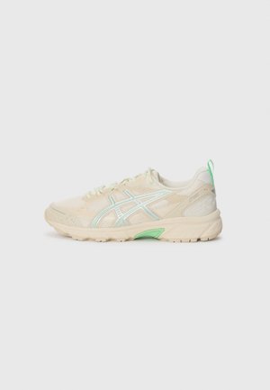 Basket athlétique crème et vert clair avec empeigne en mesh, fermeture à lacets, semelle rembourrée et logo de la marque sur le côté et la languette de talon.