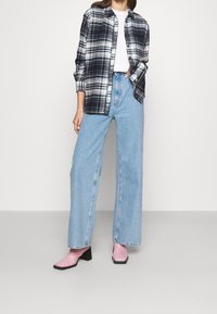 Plaid flannel shirt in navy, white, and green, paired with loose light blue jeans and pink ankle boots with a block heel.
