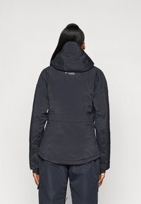 Geacă puffer de culoare bleu închis, cu glugă, talie strânsă și detalii cusute. Prezintă un logo pe spate și manșete elastice. Textură netedă.