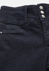 Marina denimbyxor med hög midja, med en stängning med fem knappar, en framficka och en slät, texturerad yta.