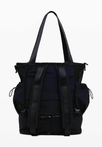 Black nylon tote bag with dual short handles, mesh side pockets, and contrasting straps. Features zippers and a textured base.