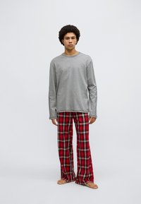 Grey long-sleeve T-shirt paired with red plaid flannel pants. The shirt features a round neckline, while the pants have a loose fit.