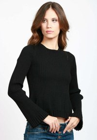 Maglione nero a coste con maniche a campana lunghe, design corto e orlo ondulato. Abbinato a jeans in denim blu.