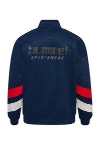 Giacca a pullover blu navy con accenti a strisce rosso, bianco e blu sulle maniche. Presenta il logo "hummel" e "SPORTSWEAR" in stampa metallica sul retro.