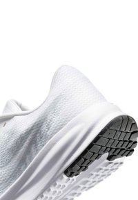 Chaussure de sport blanche avec une tige en mesh texturé, un col arrondi et une semelle extérieure en caoutchouc noir dotée d'une bande de roulement à motif pour une meilleure adhérence.