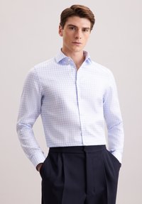  Lichtblauw en wit geruit shirt met een button-down kraag, lange mouwen en zachte stof. Gecombineerd met een donkere broek, handen in de zakken.