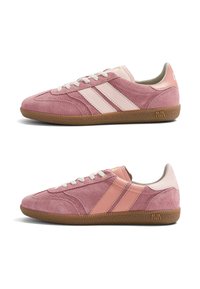 Paire de baskets en daim rose avec des rayures rose clair, des lacets blancs et des semelles en gomme, vues de profils gauche et droit.