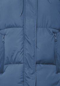 Blå puffy vest med lynlåslommer i siderne, høj krave og en glat, shiny tekstur med horisontale syede detaljer.