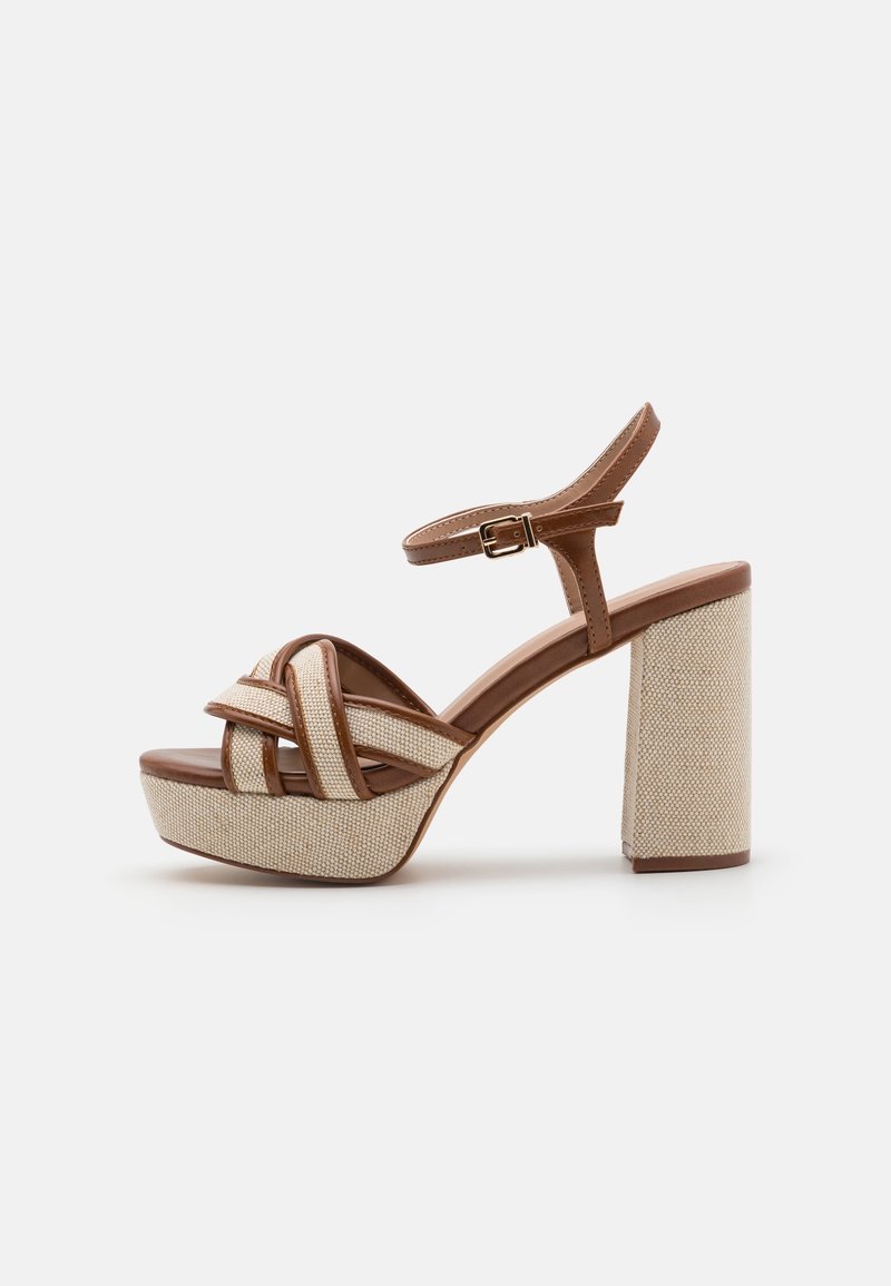 Sandale à talon haut avec plateforme tissée beige et talon bloc, bride de cheville en cuir marron avec boucle, et lanières croisées à l'avant.