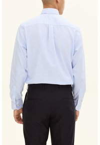 Vaaleansininen pitkähihainen paita, jossa valkoiset pystysuorat raidat. Ominaisuuksiin kuuluvat nepparit hihansuissa ja pystykaulus, yhdistetty tummiin housuihin.