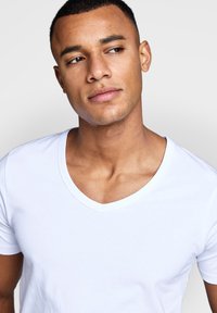 White cotton V-neck T-shirt with short sleeves, featuring a smooth texture and casual fit, highlighting the neckline and shoulder line.