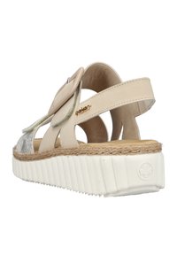 Beige sandal med ljusgröna detaljer, prydd med en stor dekorativ spänne, vävd jute-mellansula och vit gummiyttersula med räfflor.