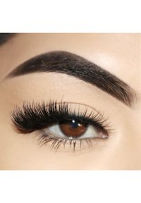 Close-up of a brown eye with long, curled black eyelashes and well-defined dark eyebrow. Smooth skin with a natural tone.