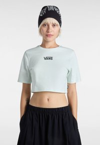 Lys mintgrøn cropped t-shirt med korte ærmer, prydet med broderet "VANS"-logo i sort på brystet. Parret med sorte shorts med snor.
