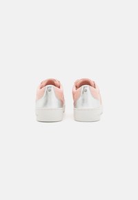 Rosa textilsneakers med en texturerad yta, silverdetaljer på hälen och en vit gummisula. Minimalistisk design med diskret profilering.
