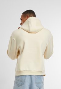 Crème-kleurige hoodie, relaxed fit met een trekkoordcapuchon, ribgebreide manchetten en onderrand, gemaakt van een gladde, textuurstof.