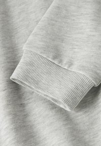 Jasnoszara tkanina z dresowej bluzy z prążkowanym mankietem. Charakteryzuje się miękką, gładką fakturą oraz subtelnym melanżowym wzorem. Funkcjonalny i casualowy design.