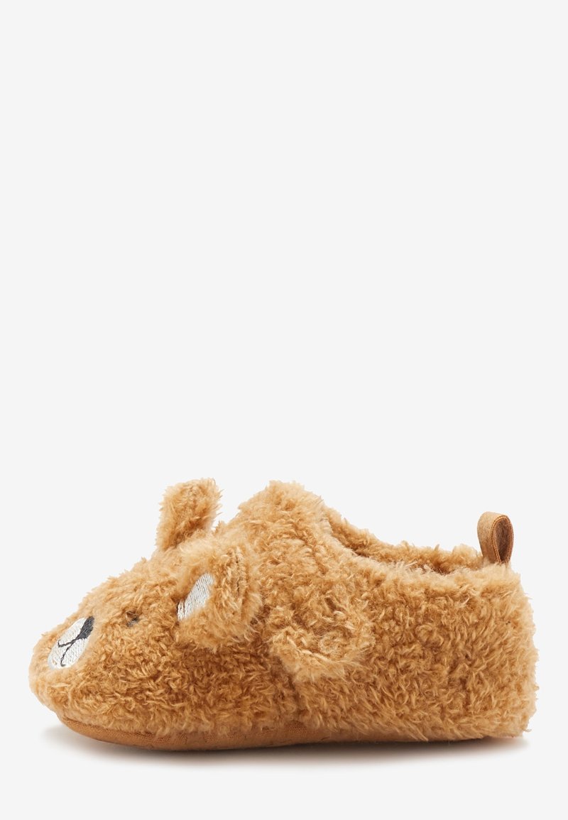 Chausson marron doux et pelucheux conçu en forme d'ours avec des oreilles, des yeux, un nez et une bouche brodés, et une languette à l'arrière du talon.