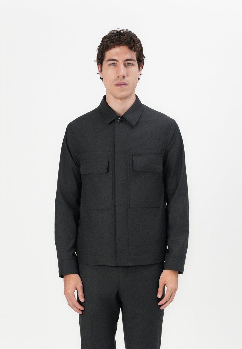 Black jacket made of textured fabric, featuring a button-up front, pointed collar, and two chest pockets with flap closures.