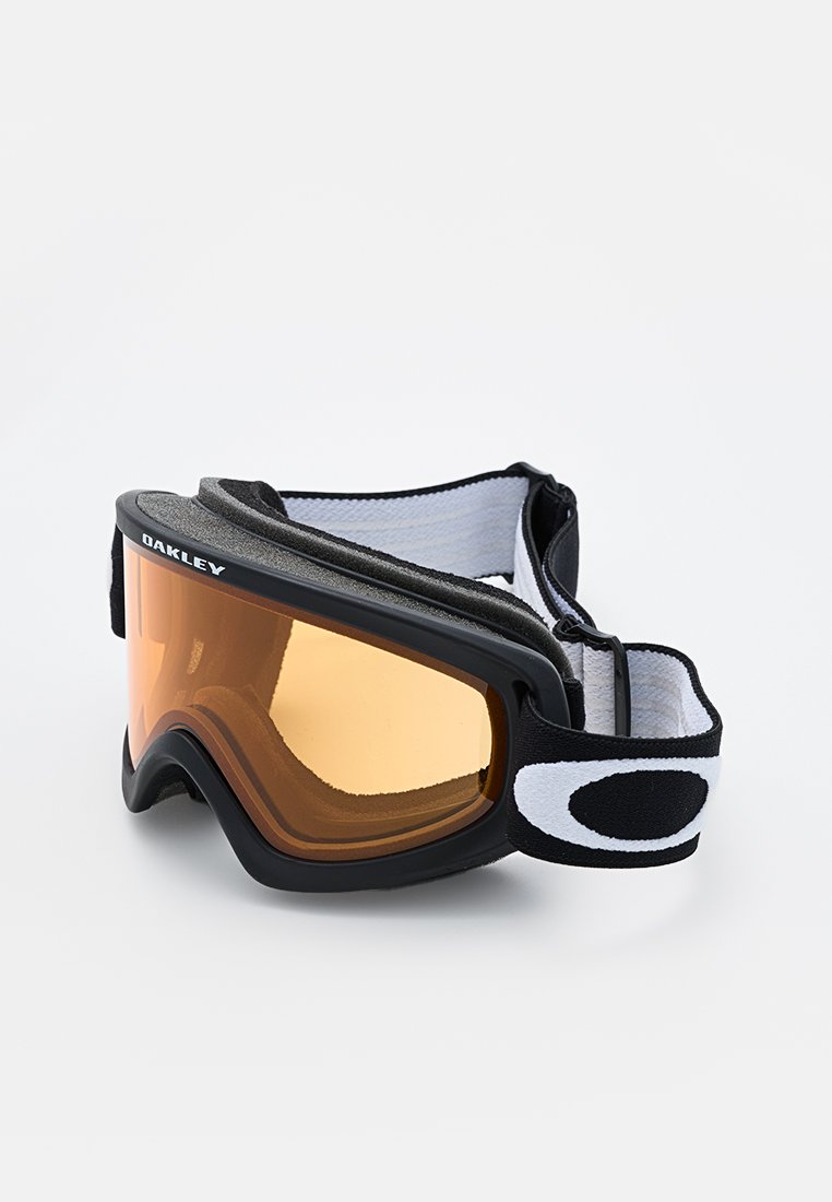 Gafas de esquí negras con lentes ámbar, que presentan un suave forro interior y una correa elástica ajustable con acentos en blanco.