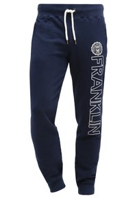 Mörkblå sweatpants i bomullsblandning med vit dragsko, med en cirkulär logotyp och ordet "FRANKLIN" tryckt vertikalt i vitt.