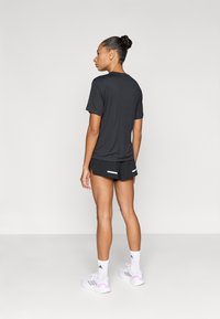 Zwart atletisch t-shirt en korte broek met een comfortabele pasvorm. Het t-shirt heeft korte mouwen en een ronde hals; de korte broek is voorzien van twee witte accenten.