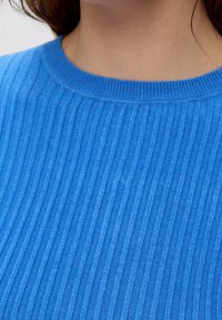 Maglione a costine blu con collo a giro e righe verticali in un tessuto morbido e testurizzato. Vista ravvicinata della parte superiore dell'indumento.