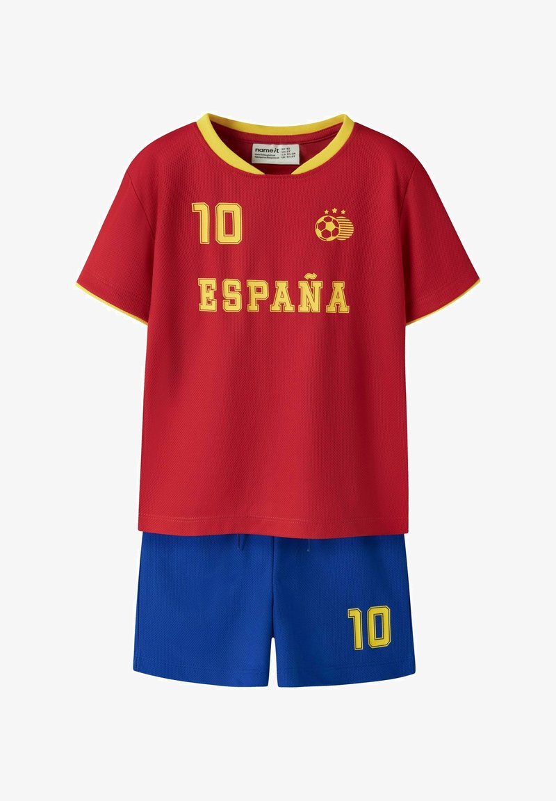Maillot de football rouge à manches courtes avec bordure jaune, "10" et "ESPAÑA" en jaune, associé à un short bleu avec un "10" jaune sur la jambe.
